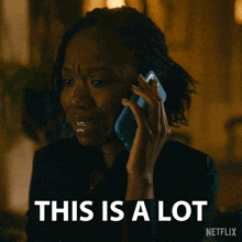 a woman is crying while talking on a cell phone with the words " this is a lot " behind her