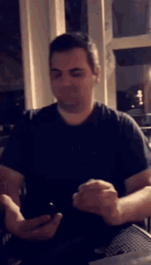 a man in a black shirt is looking at his cell phone