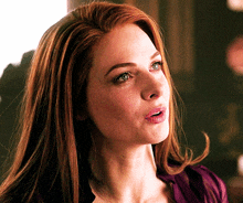 a close up of a woman 's face with red hair and green eyes