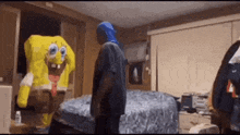 a man in a blue hood is standing next to a spongebob inflatable in a bedroom .