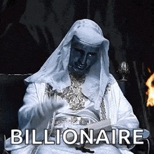 a man in a white robe is sitting in front of a fire with the word billionaire written on the bottom