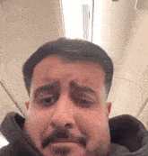 a man with a mustache is making a funny face while sitting on a plane .