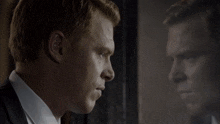 a man in a suit looks at his reflection in the mirror