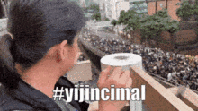 a woman is holding a roll of toilet paper in front of a crowd with the hashtag #yijincimal