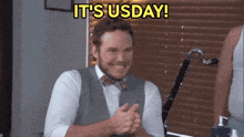 a man in a vest and bow tie is clapping and smiling with the words it 's usday above him