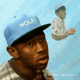 a man wearing a blue hat with wolf on it