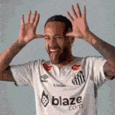 a man wearing a white shirt with the word blaze on it sticks his tongue out