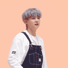 a young man wearing overalls and a headband is giving a thumbs up