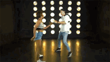 a man and a woman are dancing together on a stage in a dark room .