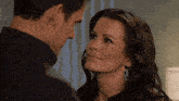 a man and a woman are looking at each other and the woman is wearing earrings