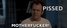 a man in a white shirt is standing in a room with the words `` pissed motherfucker '' written on his face .