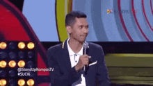 a man in a suit is holding a microphone in front of a stage .