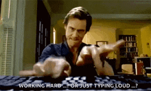 a man is typing on a computer keyboard and pointing at the camera .