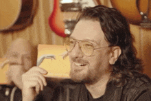 a man with glasses and a beard is smiling in front of a guitar display .