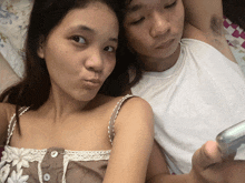 a man and a woman are laying on a bed and the woman is making a face