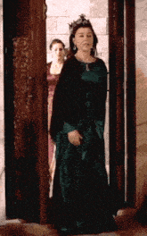 a woman in a green dress is standing in a doorway .