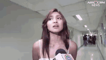 a woman is holding a microphone in a hallway and talking into it .
