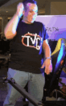 a man wearing a tmc shirt adjusts his earphones