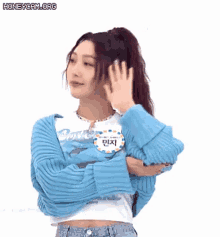 a woman in a blue sweater and a blue shirt is making a fist gesture .