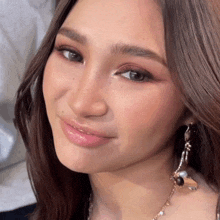 a close up of a woman 's face with a necklace and earrings