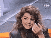 a woman with curly hair is smiling in front of a sign that says tof