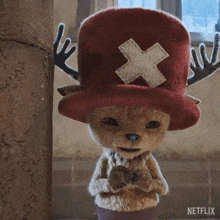 a stuffed animal wearing a red hat with a white cross on it