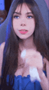 a girl with long hair and blue eyes is wearing a blue dress and holding a white object .