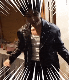 a man wearing a leather jacket and a white tank top is dancing in a room .