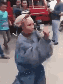 a woman in a blue sweater is dancing in front of a crowd of people .