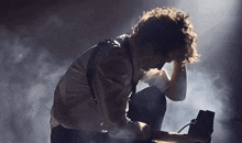 a man is kneeling down with his hands on his head