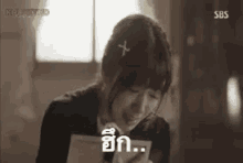 a woman is crying while holding a piece of paper in her hand and looking at it .
