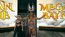 two women are standing in front of a mega bayn sign