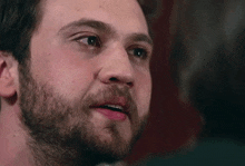 a close up of a man 's face with a beard and a tear coming out of his eye .