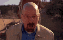 a bald man with a beard and glasses is standing in front of a building .