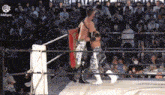 two men are wrestling in a ring with a crowd of people watching .