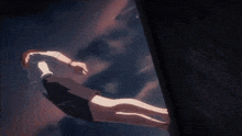 a woman in a white shirt and black shorts is hanging from a rope in the air