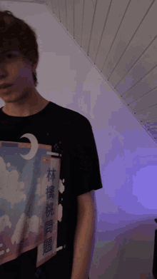 a young man wearing a black t-shirt with chinese writing on the front