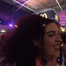 a woman smiles in front of a mcdonalds sign