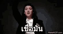 a woman in a tuxedo is dancing with her hands in the air .