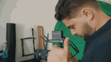 a man taking a picture with a camera with a green screen in the background