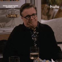 a man sitting at a table with a glass of wine in front of a sign that says " mid century modern "
