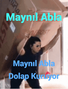 a woman is lifting a large cardboard box with the words maynil abla dolap kuruyor on the bottom