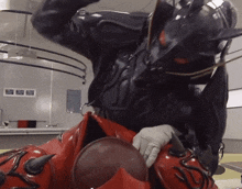a person in a devil costume is holding a red ball