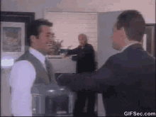 a man in a suit and tie is standing next to another man in an office .