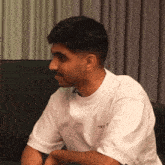 a man wearing a white t-shirt that says true is sitting on a couch