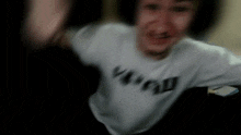 a blurry picture of a man wearing a white shirt with the word vogue on it