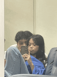 a man and a woman are taking a selfie in front of a mirror