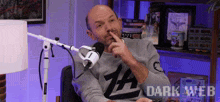 a man sitting in front of a microphone wearing a shirt that says dark web on it