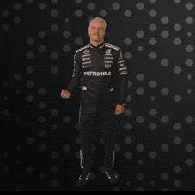 a man in a petronas uniform stands in front of a dark background
