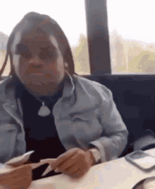 a woman with dreadlocks is sitting at a table with a knife and fork .